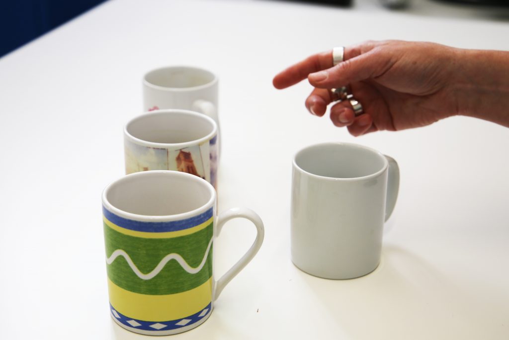 Someone choosing between similar but different coffee mugs